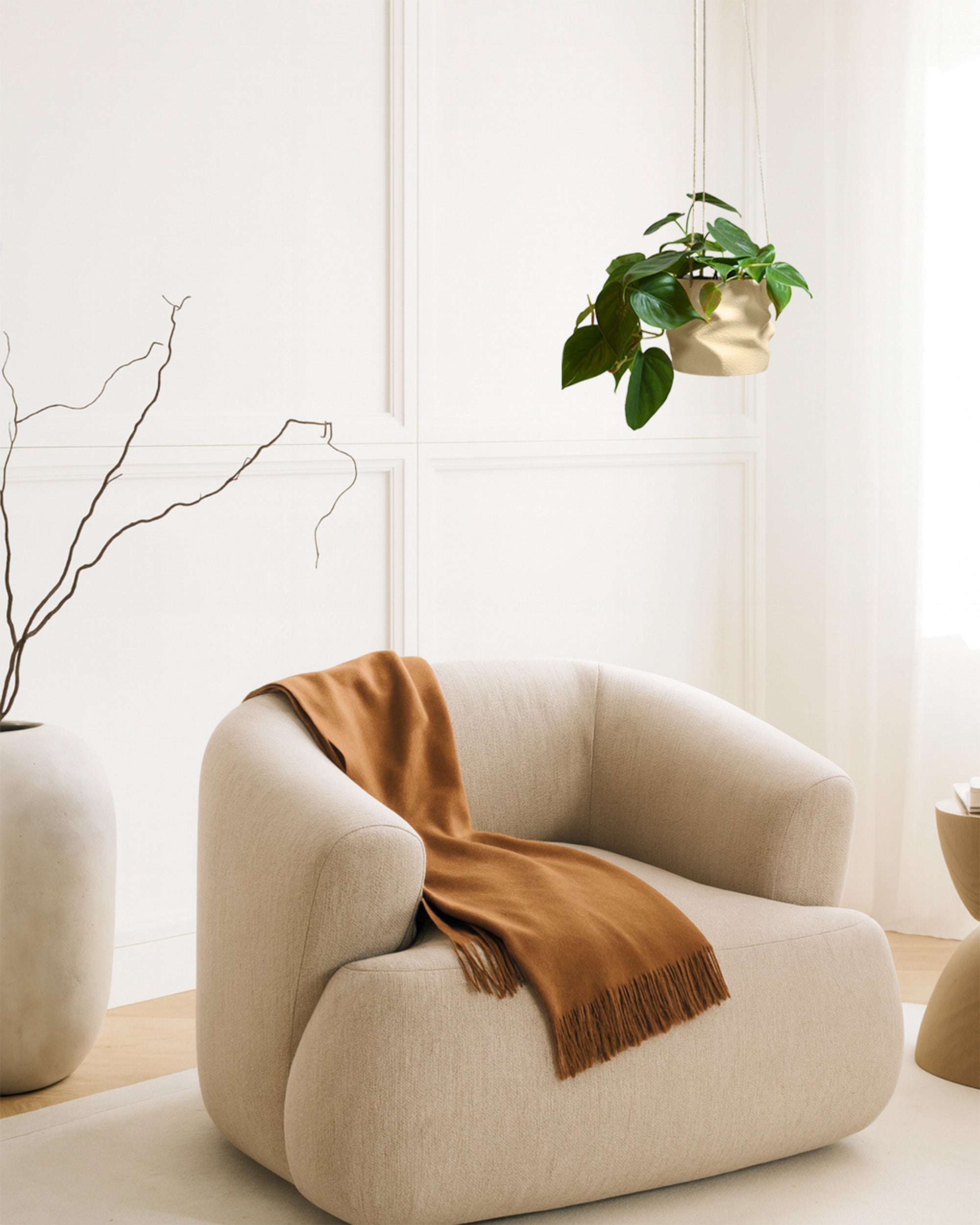 Philodendron in moderner Hängeampel über einem Sessel im hellen Wohnzimmer